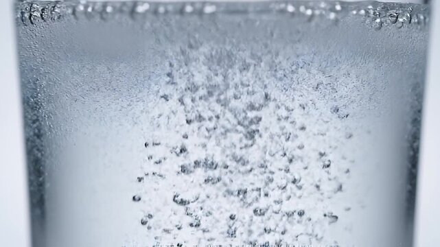 Effervescent tablet dissolving and bubbling in a glass of clear water