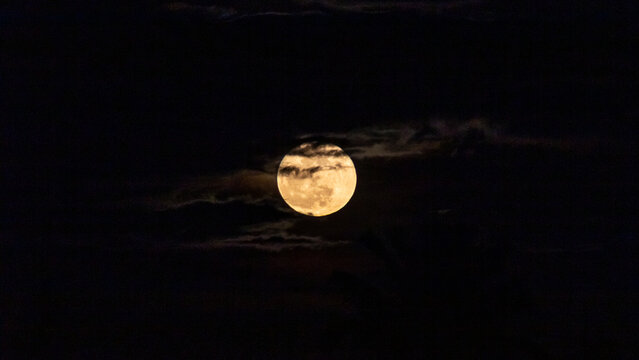 Full moon in the night sky with clouds