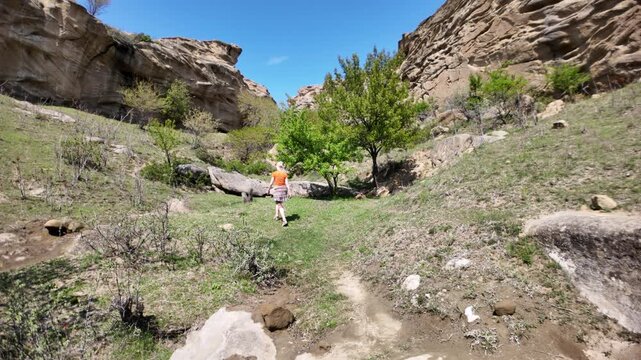 Woman walking a path, exploring the ancient rock-hewn structures and natural landscape of Uplistsikhe cave city, a significant archaeological site and museum-reserve in Georgia