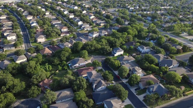Slickrock Creek basin borders master planned community dense housing single family suburban houses near Highway 151. Curved turnarounds feature parked cars along leafy oak trees, San Antonio, TX