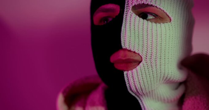 Woman wearing split black and white balaclava. Mysterious female character in mask representing duality and anonymity. Concept of hidden identity and subculture fashion.