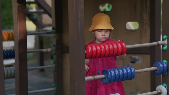 Little girl playing with colorful abacus on playground. Child learning basic counting and logic with educational toy. Preschool education and fun outdoor activity for young kid.
