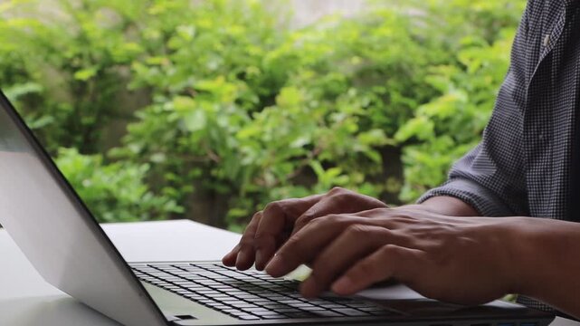 Close up of male hands typing on laptop keyboard, professional person working on notebook computer in cafe, remote work and digital nomad lifestyle.