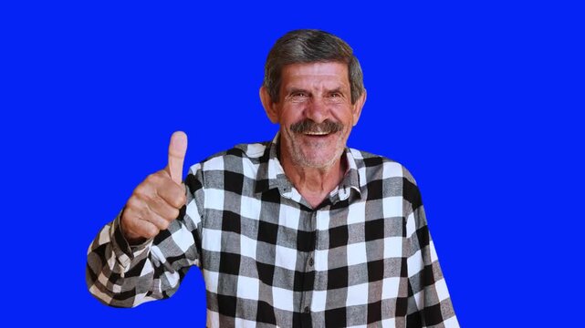 Happy senior man giving thumbs up on blue chroma key background. Smiling elderly male approving with positive gesture for advertising. 4K video.