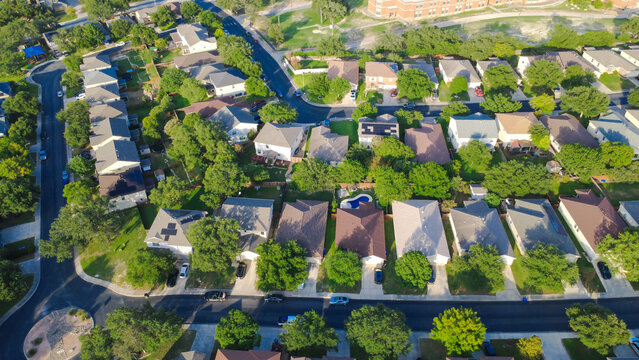 West Military Drive frames dense residential rooftops displaying prominent solar arrays within Magnolia Heights. Angular rooflines complement swimming pools and yards, San Antonio, Texas