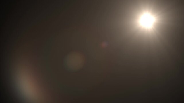 Sunlight flare illuminates the dark atmosphere creating a soft radiant glow in the upper corner of the frame.