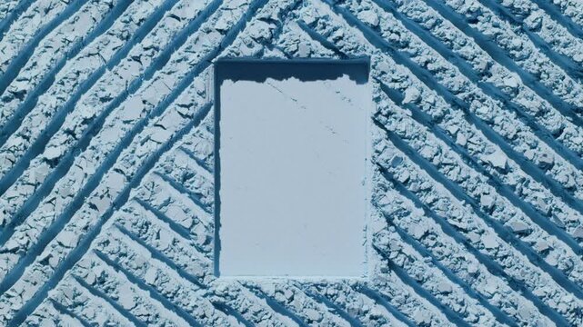 Overhead shot of a pale blue powder surface with intersected furrows and rectangular texture, highlighted by orbiting directional light throwing shifting shadows
