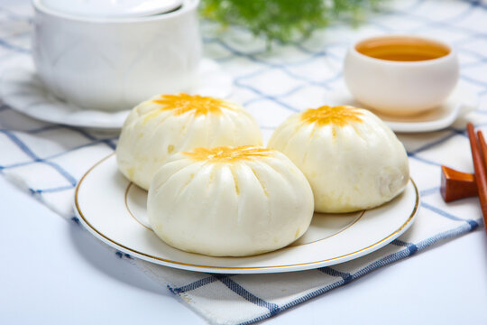 Three pan fried buns on blue and white porcelain plate tea chopsticks dark cloth