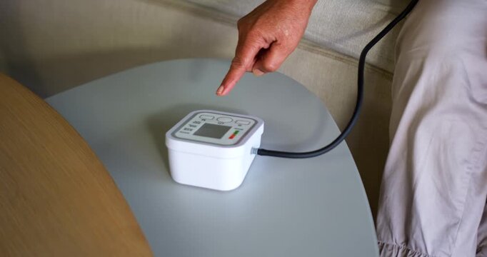 Senior African American woman pressing control pad on white unit on sofa table, adjusting settings