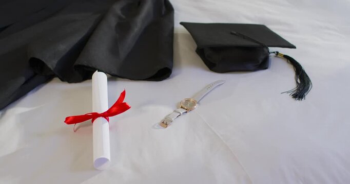 Camera starting to record is showing rolled diploma arranged on white bed as graduation display