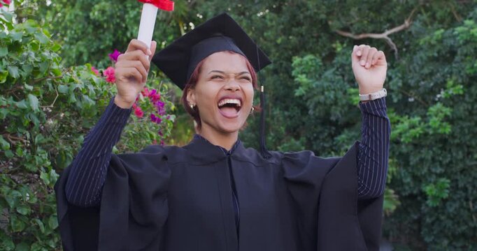 African American woman celebrating graduation holding diploma waving laughing in gown cap in garden