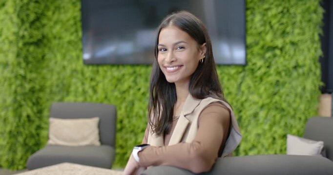Camera filming African American woman smiling turning in blazer showing smartwatch in office lounge