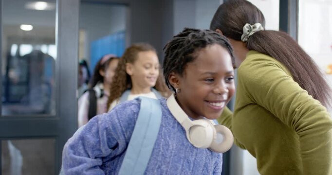 African American woman welcoming children entering class holding door giving fist bumps, copy space