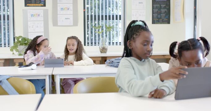 African American child girls using tablet in class as teacher entering raising hand high-fiving