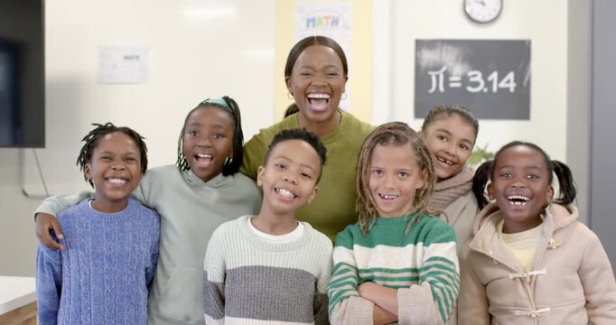 Diverse class, African American teacher looking right, laughing, students smiling at board ?=3
