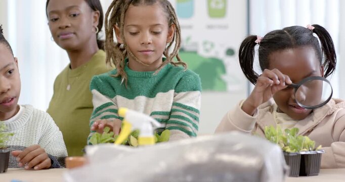 Class kids after teacher prompt inspecting seedlings with magnifier and microscope studying growth