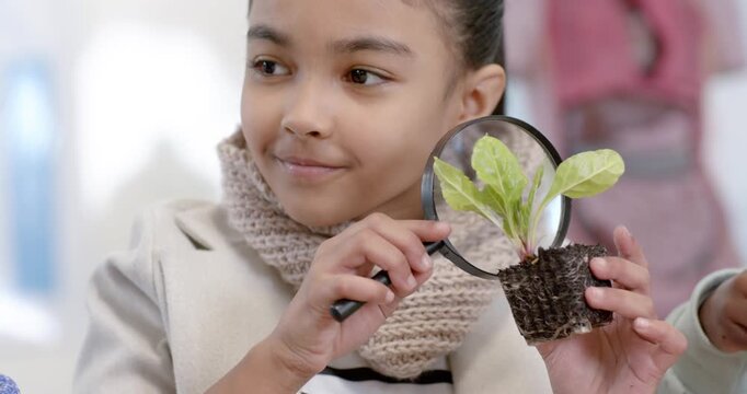 African American teen girl getting curious bringing lens inspecting seedling in peat pot at school