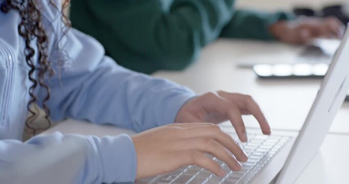 Students teen girl typing on laptop camera pulling back revealing peer finishing work, copy space
