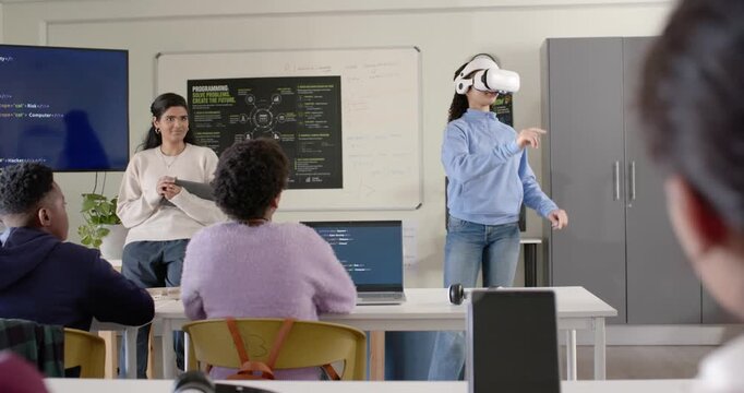 Teacher guiding demo while youth putting on VR headset reaching interacting with code, copy space
