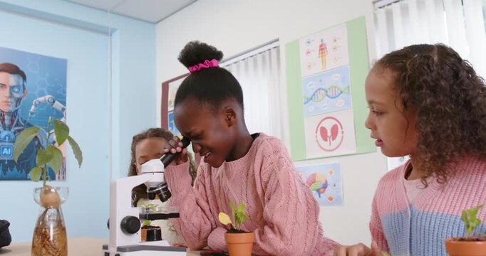 Child girls leaning during lab center girl peering into microscope adjusting focus for plant study