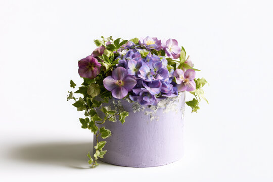 Soft lavender celebration cake overflowing with hydrangea, pansy, ivy and delicate blossoms, accented with silver leaf in an elegant botanical design on white.