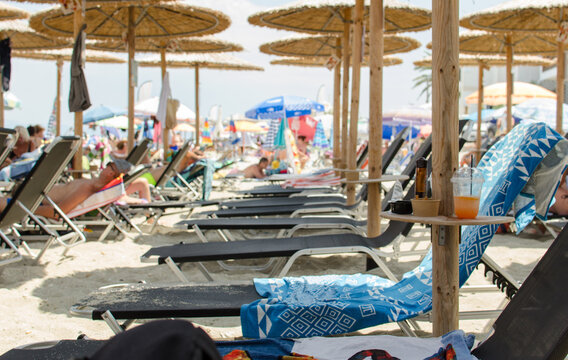 4th July 2026 - Halkidiki, Pefkohori, Greece. Sunbeds on the sandy beach under natural reed umbrellas.