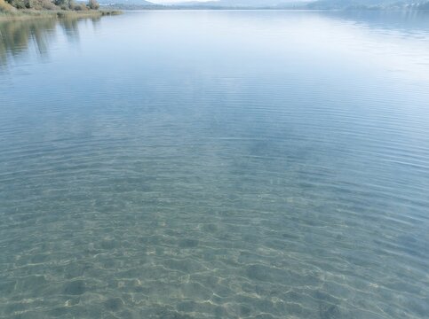 Calm lake water surface with clear shallow depths and distant shoreline.