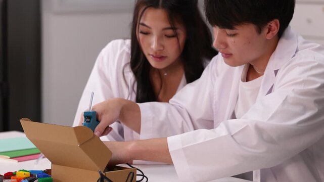 Teenage Students Using Hot Glue Gun for Science Project in Classroom