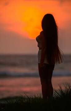 Silhouette of a woman watching the sunset on the beach