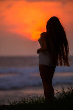 Silhouette of a woman standing on beach at sunset