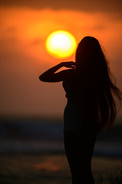 Silhouette of a woman standing on the beach at sunset 