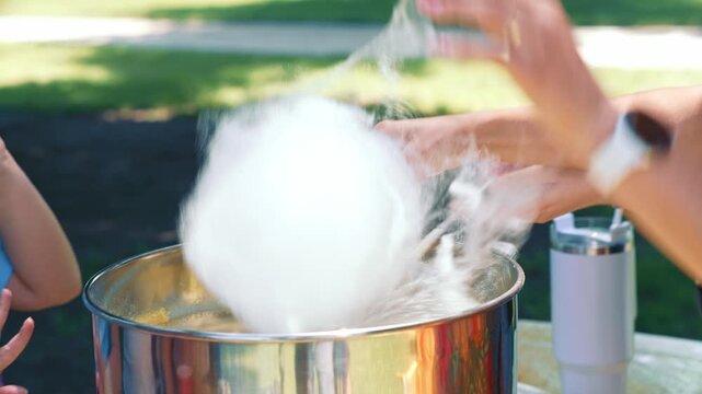 Making Large White Cotton Candy For Child Customer showing the creation of a fluffy sweet dessert at a festive event for family recreation and entertainment