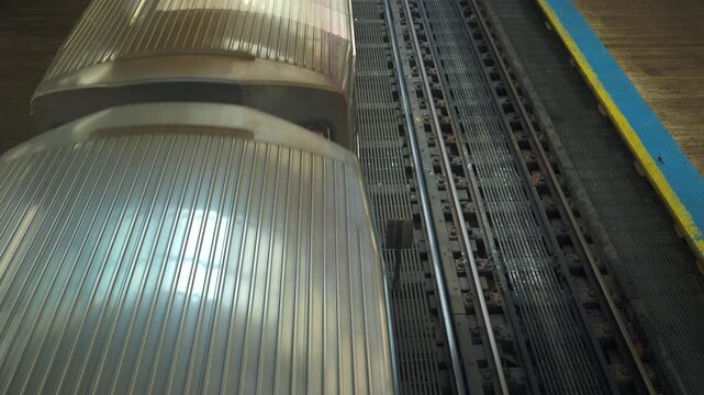 Metro train arrives on elevated tracks at a city station platform viewed from above. Detailed railway lines and urban infrastructure highlight public transportation and movement.