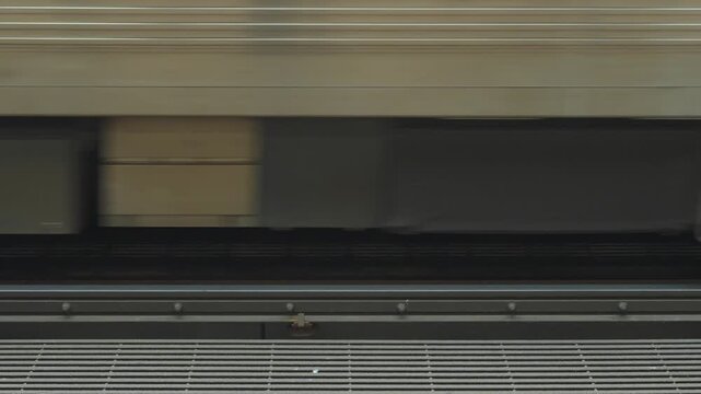 Close-up view of subway train wheels and undercarriage moving along railway tracks in a city transit system. The motion highlights industrial urban transportation infrastructure.