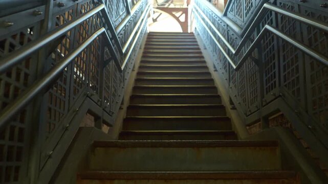 A close view of a worn metal staircase shows rust and aging textures inside a train station. The image highlights industrial materials and the passage of time in urban infrastructure.