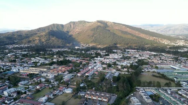 Video con drone sobrevolando una ciudad en un valle de Quito con una monta&ntilde;a de fondo durante el atardecer 