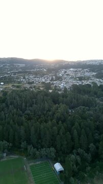 Video con drone sobrevolando un parque con una ciudad de fondo durante el atardecer 