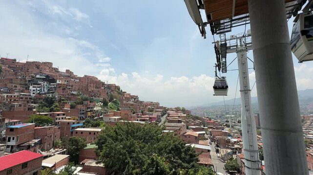 Aerial view of Metrocable cable car passing over dense hillside neighborhoods in Medellin, Colombia