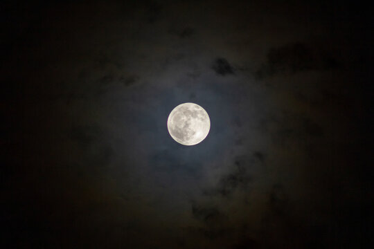 Full moon in the night sky with clouds