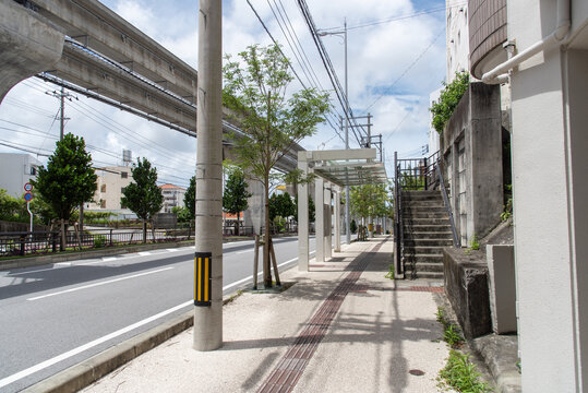 モノレールの軌道とバス停留所のある快晴の車道と点字ブロックのある歩道