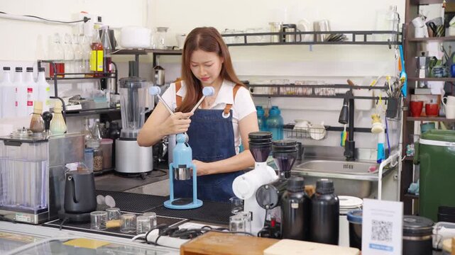 Small business entrepreneur coffee shop cafe restaurant. Asian woman barista using manual espresso maker making freshly brewed coffee on bar counter. Waitress serving beverage drink to customer.