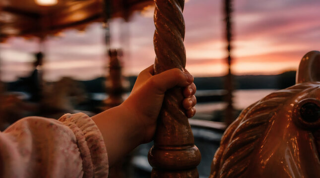 Childs Hand Gripping Carousel Pole During Sunset