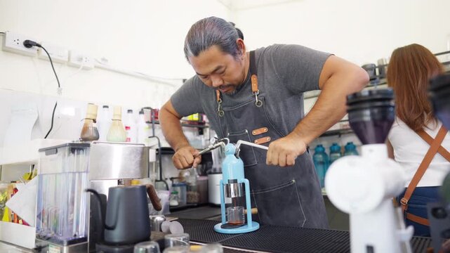Small business entrepreneur coffee shop cafe restaurant. Asian man barista using manual espresso maker making freshly brewed coffee on bar counter. Waitress serving beverage drink to customer.