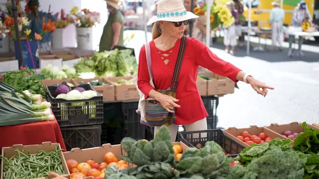 Mature woman smiles as she selects fresh produce at the farmers market in Sonoma California on a sunny morning in the valley