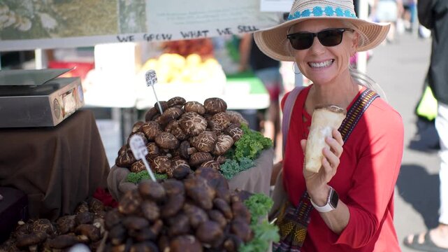 Happy senior woman shops for fresh shiitake mushrooms at the Sonoma Farmers Market on sunny morning with bright smiles.
