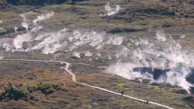 Visitors walk along boardwalks through Craters of the Moon, a geothermal park in Taupo, New Zealand, exploring active volcanic steam vents.