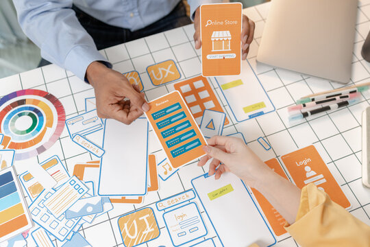 UX designers collaborate using wireframes, mobile app mockups, interface cards, and planning tools to develop user centered digital products, improving usability, design strategy, and teamwork.