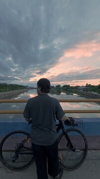 Cyclist Standing on Bridge at Sunset