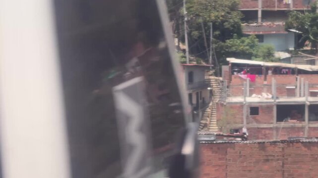 Elevated view from Metrocable looking down upon dense red brick hillside housing in a Medell&iacute;n comuna, Colombia