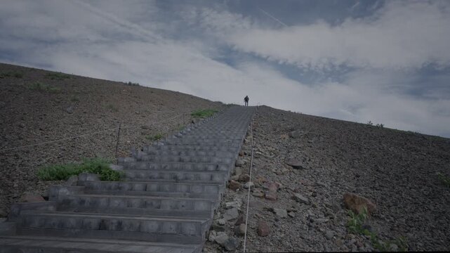 火山礫に囲まれた階段を登っていく人